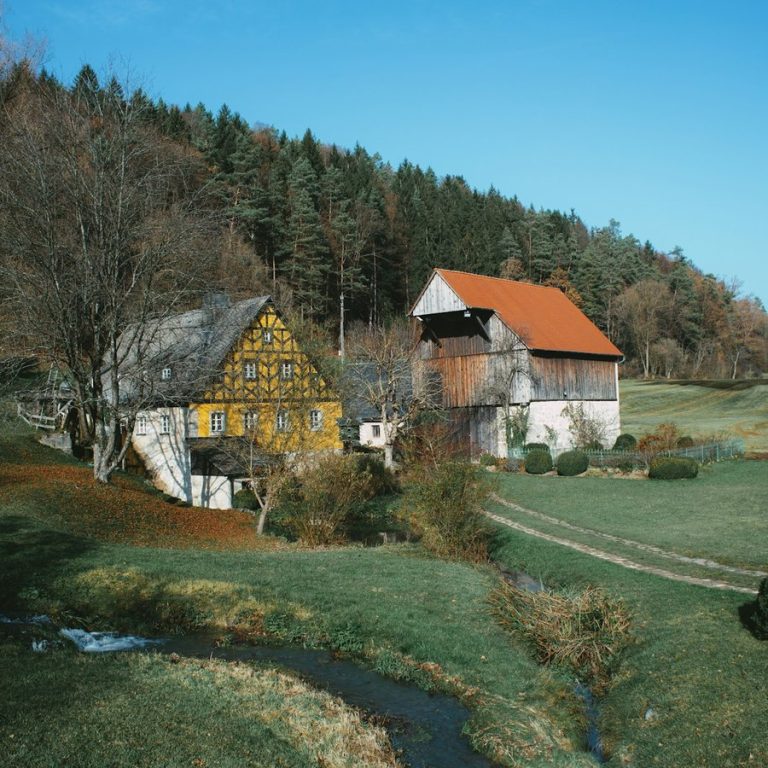 Erfahrener Immobilienmakler Lichtenau: Fachwerkhäuser an einem Bach am Waldrand