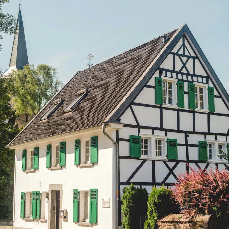 Immobilie schnell verkaufen Tuchenbach: Fachwerkhaus mit grünen Fensterläden und Kirchturm