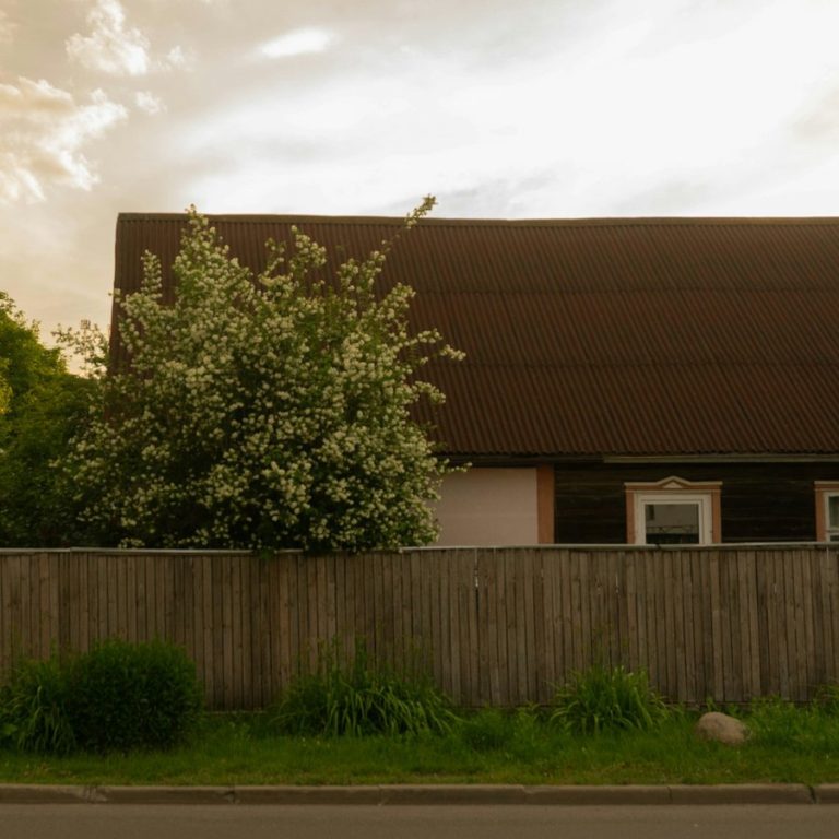 Immobilienmakler Hagenbüchach: Wohnhaus hinter einem Holzzaun im Abendlicht